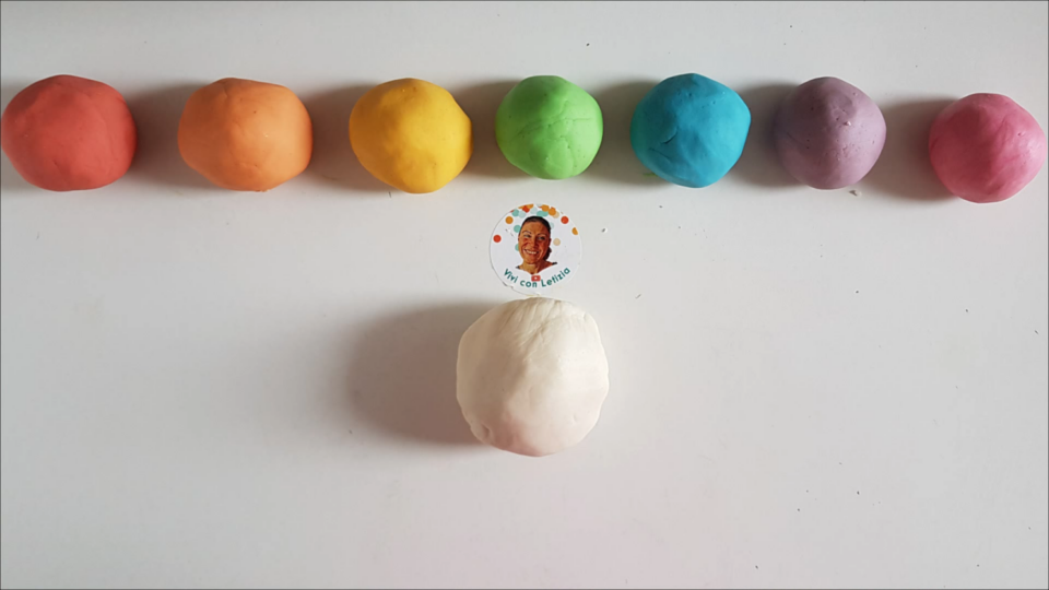 Pallina di pasta di sale neutra e palline di impasto colorato di rosso, arancione, giallo, verde, azzurro, viola e fuxia