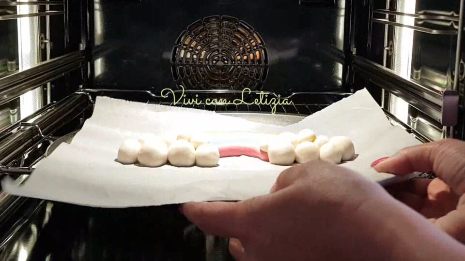 Teglia ricoperta di carta da forno con oggetto che sta per essere infornato da cuocere