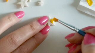 mani che dipingono una stellina di pasta di sale con colori acrilici