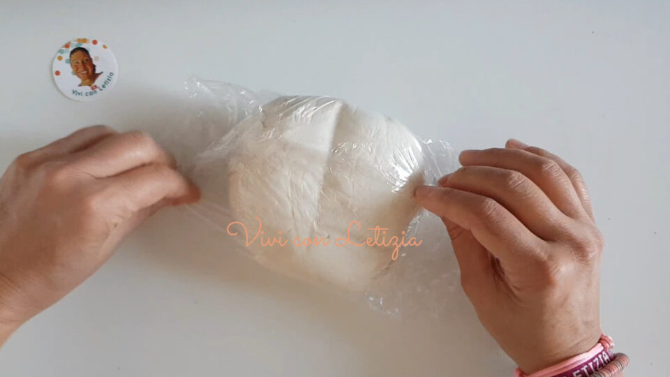 Mani che avvolgono l'impasto della pasta di sale nella pellicola per farlo riposare